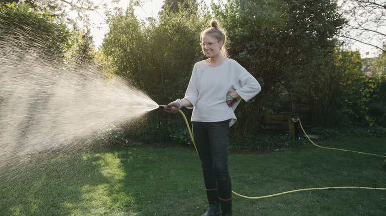 A woman watering her lawn with a hose.
